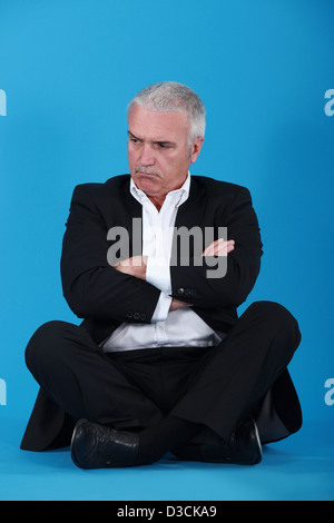 wütend senior Geschäftsmann sitzt im Schneidersitz Stockfoto