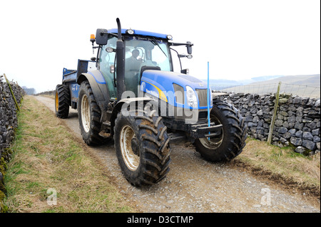 Große blaue Traktor ziehen eines Anhängers entlang bei Maultierweg oberhalb des Dorfes Clapham in den Yorkshire Dales, England. Stockfoto