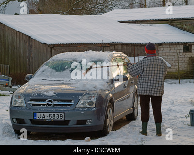 Frau, die Beseitigung von Schnee vom Auto im winter Stockfoto