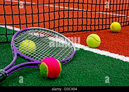 Ball und Tennis Schläger um das Netz auf einem synthetischen Feld angeordnet. Stockfoto