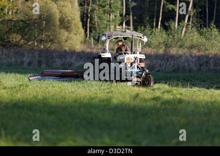 Strahlende Dorf, Deutschland, Landwirt auf einen Traktor, einen Rasen zu mähen Stockfoto