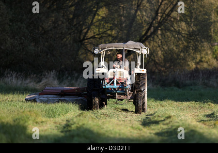 Strahlende Dorf, Deutschland, Landwirt auf einen Traktor, einen Rasen zu mähen Stockfoto