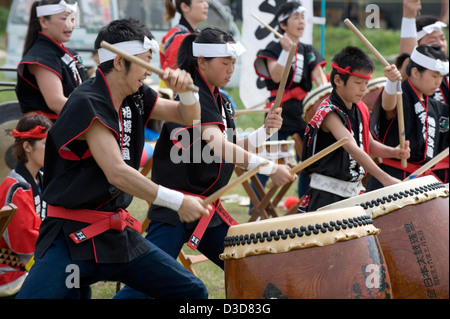 Ein Team von energetischen Trommler jung und alt schlagen einen musikalischen Rhythmus auf Odaiko Japanisches Trommeln mit Holzschlegel auf einem Festival. Stockfoto