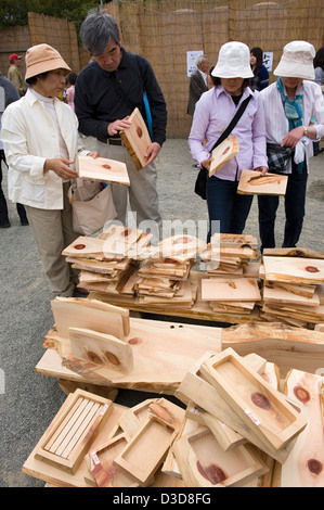 Neugierig Shopper inspizieren Platten aus Holz und waren aus duftenden Hinoki oder japanischer Zypressenholz, auf einem Outdoor-Flohmarkt. Stockfoto