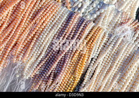 Tausende von Strängen von Glasperlen in Pastell-Farben sind auf dem Display in der Sonne am Nachmittag. Stockfoto