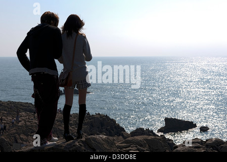 Junges Paar nimmt im Hinblick auf glitzernde sonnige Meer hoch über der zerklüfteten, felsigen Küste von Meer von Japan in Tojinbo, Fukui, Japan Stockfoto