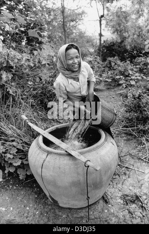 Prey Veng Provinz, Kambodscha: eine junge Frau den Haushalt Glas Wasser füllt sich mit Wasser aus einem Brunnen. Stockfoto