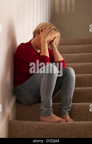 Blonde Frau sitzt allein auf der Treppe, Kopf in Händen verärgert oder Weinen. Stockfoto