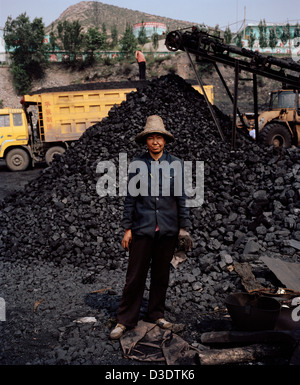 DATONG, Provinz SHANXI, CHINA - AUGUST 2007: Wang Yue Ping, 46, steht vor einem Haufen Kohle an einer Kohle-Lieferung-Station, wo sie arbeitet. Stockfoto