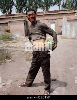 DATONG, Provinz SHANXI, CHINA - AUGUST 2007: Hält ein junger Bergmann, der nur aus Verschiebung gekommen ist eine Wassermelone Stockfoto