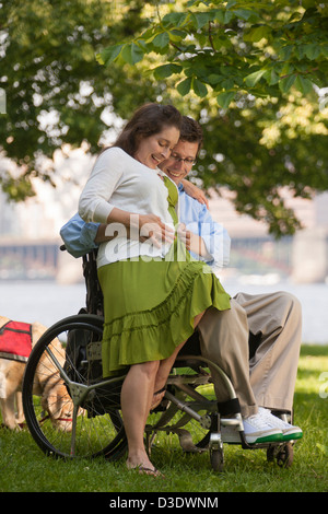 Mann mit einer Rückenmarksverletzung in einem Rollstuhl Gefühl seine Frau Babybauch Stockfoto