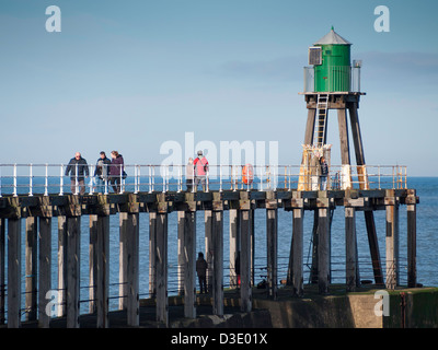 Menschen zu Fuß auf Whitby West Pier Ausdehnung an einem sonnigen Wintertag Stockfoto