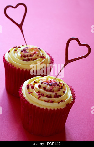 zwei leidenschaftliche Tesco Finest Himbeer Cupcakes mit herzförmigen Schatz Wunderkerzen auf rosa Hintergrund isoliert Stockfoto