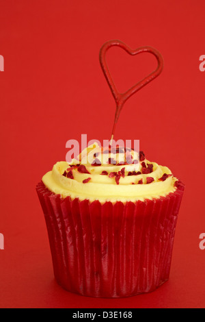 Tesco Finest leidenschaftliche Himbeer Cupcake mit Herz geformten Schatz Wunderkerze auf rotem Hintergrund isoliert Stockfoto
