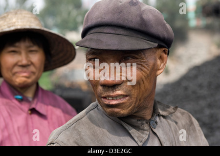 DATONG, Provinz SHANXI, CHINA - AUGUST 2007: Li Yu, 64, nimmt eine Auszeit von der Sortierung Kohle auf einem Förderband in einem privaten mine in der Nähe von Datong. Stockfoto