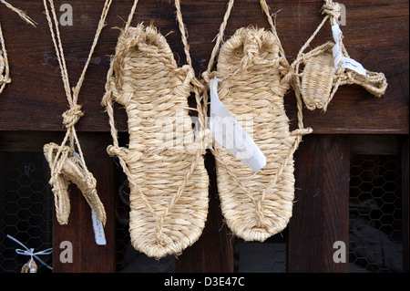 Mehrere Paare von traditionellen Waraji Schuhe, Stroh Sandalen, hängen an der Pforte des Tempels Zenkoji in Nagano. Stockfoto