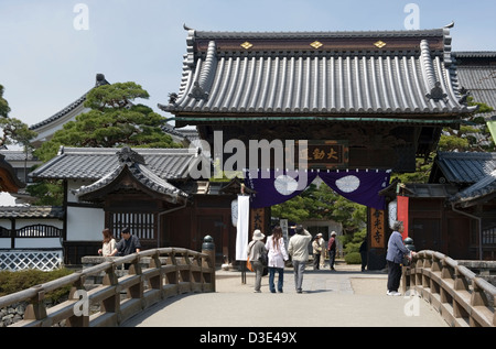 Besucher, die über eine Brücke an einem kleinen Sub-Tempel auf dem Gelände der Tendai-Sekte Zenkoji Buddhistentempel in Nagano. Stockfoto