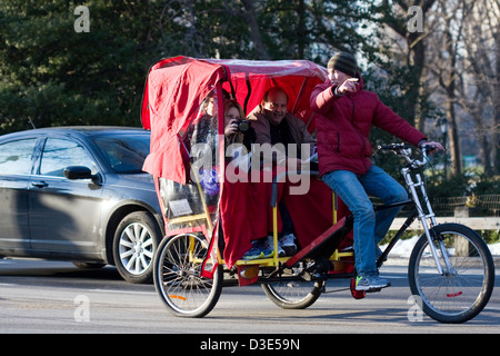 Rikscha-Fahrer weist darauf hin, interessante Sehenswürdigkeiten, wie ein Tourist ihre Kamera zu fotografieren Central Park in New York City bereitet. Stockfoto