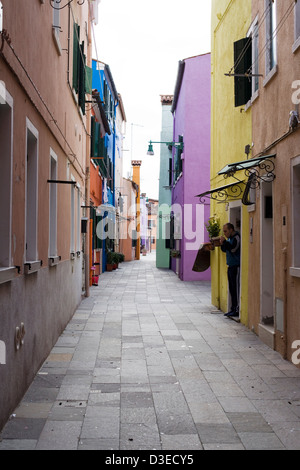 Mann in einem Hauseingang, zündet sich eine Zigarette auf der Insel Burano Stockfoto