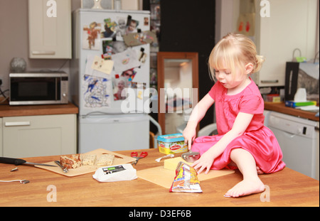 Kleinkind sitzt alleine auf einem Küchentisch Butter Essen Stockfoto