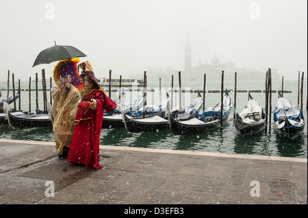 Karneval-Teilnehmer posieren für Fotografen an Venedigs Waterfront bei starkem Schneefall. Stockfoto