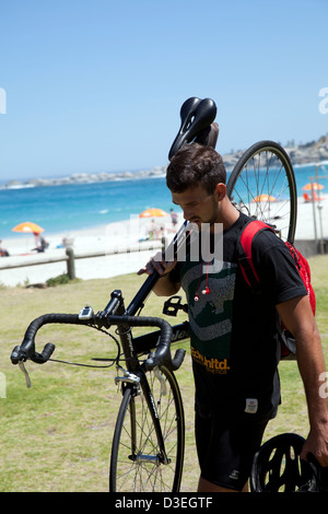 Mann mit Fahrrad auf Schulter am Strand von Camps Bay - Kapstadt Stockfoto