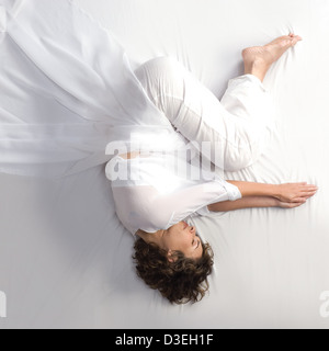 Frau in der fötalen Position auf weißem Hintergrund Stockfoto