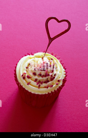 Tesco Finest leidenschaftliche Himbeer Cupcake mit Herz geformt Schatz Wunderkerze auf rosa Hintergrund isoliert Stockfoto