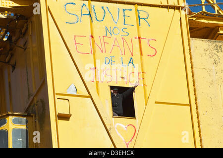 Serge Charnay Gesten, Menschen unterhalb von seiner Position in einer 40 Meter hohen Werft Kran in Nantes, Frankreich, 18. Februar 2013. Charnay kletterte den Kran am 16 Februar, eine gerichtliche Entscheidung verweigert ihm Zugang zu seinem Sohn zu protestieren. Stockfoto