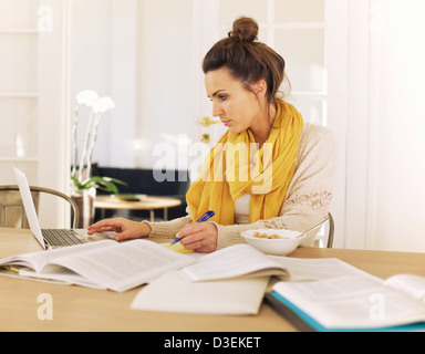 Junger Student mit Laptop und Bücher an einem Studium von zu Hause Stockfoto