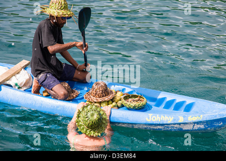 Frau Tourist schwimmt, eines Verkäufers Kanu einen Hut aus Bananenblättern Palm, St Lucia anprobieren. Stockfoto