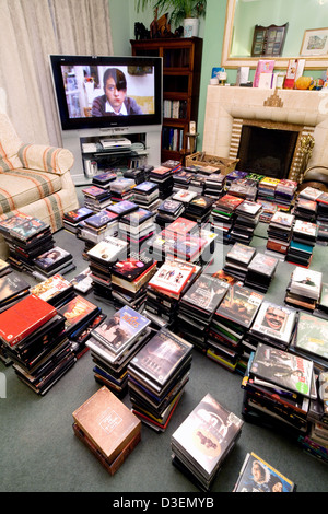 Eine große DVD-Sammlung von DVDs von Film und Fernsehen mit einem Großbild-TV in einem Privathaus, UK Stockfoto