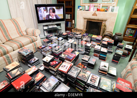 Eine große DVD-Sammlung von DVDs von Film und Fernsehen mit einem Großbild-TV in einem Privathaus, UK Stockfoto