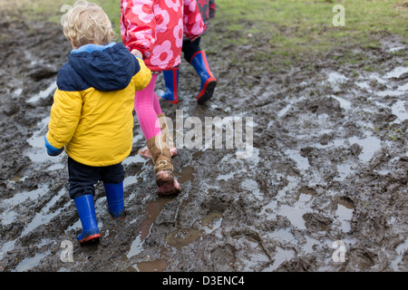 Kinder zu Fuß durch schlammigen Pfützen Stockfoto