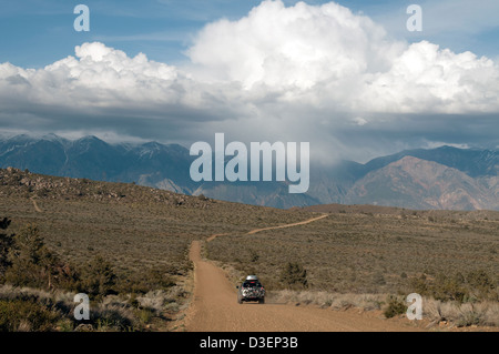 4WD Auto fährt auf einer unbefestigten Straße auf einem Roadtrip durch Owens Valley, Kalifornien in der Nähe von Bischof auf dem Weg zum Red Canyon bei Sonnenuntergang. Stockfoto