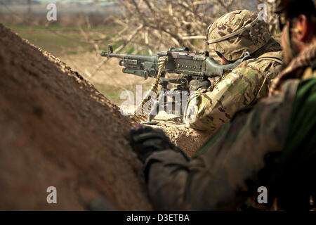 Ein US-Marine wacht mit einem schweren Maschinengewehr als Afghan National Army Special Forces Soldaten aus einem Kampf Patrouille zurück 17. Februar 2013 in der Provinz Herat, Afghanistan. Präsident Barack Obama kündigte während der Staat der Union, dass die Hälfte die US-Force in Afghanistan von Anfang 2014 zurückziehen wird. Stockfoto