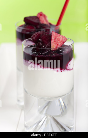 Zwei Gläser hausgemachte Joghurt Quark Dessert mit Heidelbeeren und Apfelscheiben auf grünem Hintergrund Stockfoto