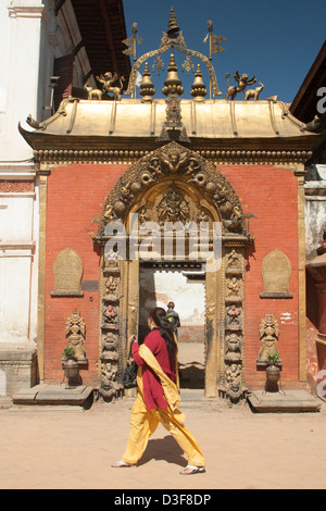 Frau zu Fuß vorbei an religiöse Monument in Nepal tagsüber tragen traditionelle Kleidung Stockfoto
