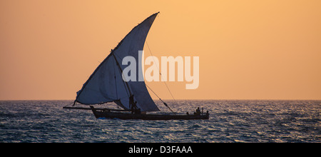 Fischer fahren ihre Dhau in den Sonnenuntergang vor der Küste von Sansibar, Tansania. Stockfoto