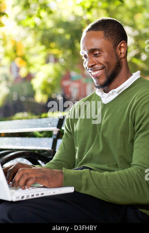 Schwarze Amerikaner in ein Stadtteilpark mit der Bequemlichkeit des Wifi für Internet. Foto aufgenommen im New Yorker East Village Stockfoto