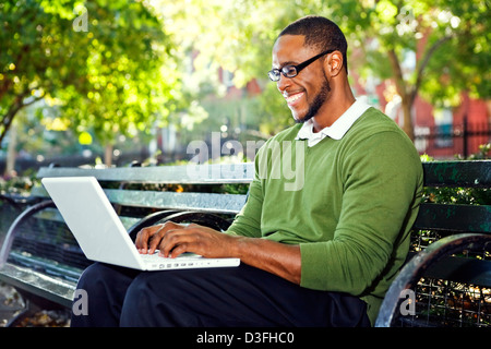 Schwarze Amerikaner in ein Stadtteilpark mit der Bequemlichkeit des Wifi für Internet. Foto aufgenommen im New Yorker East Village Stockfoto