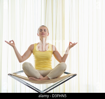 Junge Frau, meditieren auf moderner Stuhl Stockfoto