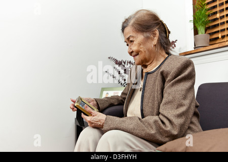 Eine weibliche Senioren 80 plus Jahre hält gerahmtes Foto von geliebten Menschen. Stockfoto