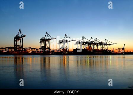 A Blick über den ruhigen Gewässern des Flusses Elbe auf den beleuchteten Containerterminal Hamburg-Altenwerder und Ladekrane, die hoch über der Küste in der Abendsonne in Hamburg, Deutschland 14. Juli 2003. Das Terminal ist eine neue Installation, die bis zum Jahr 2004 voll funktionsfähig sein wird.   Stichwörter: Quellen, HUM, Wirtschaft-Business-Finanzen, EBF, Kräne, hoch aufragenden, River el Stockfoto