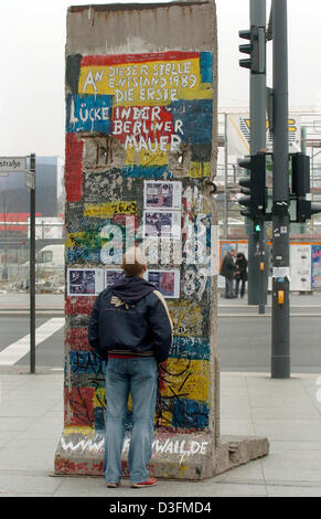 (Dpa) - ein Mann betrachtet ein Teil der ehemaligen Berliner Mauer, die auf dem Display am Potsdamer Platz in Berlin, 4. November 2004 ist. Die Graffiti an der Spitze liest "Ein Artikelwort Stelle entwicklungspädagogische 1989 Die Erste Lücke in der Berliner Mauer" (dieser Punkt markiert die erste Lücke in der Berliner Mauer im Jahr 1989). Stockfoto