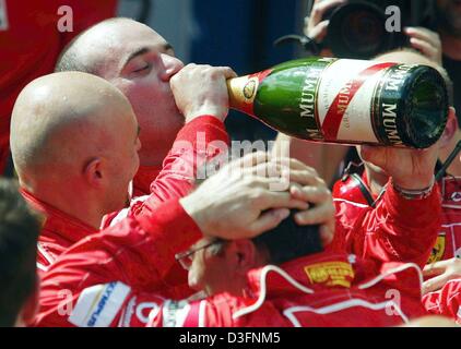 (Dpa) - Mechanik des Ferrari-Teams feiern den Sieg des deutschen Formel-1-Weltmeister Michael Schumacher mit einer Flasche Champagner nach dem Gewinn des grand Prix von Österreich auf dem A1-Ring Rennstrecke in Spielberg, Österreich, 18. Mai 2003. Stockfoto