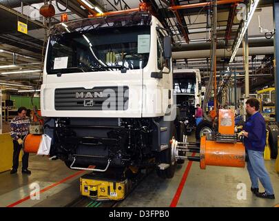 (Dpa) - zwei Arbeiter der Nutzfahrzeug-Hersteller Mann Put die Veredelung berührt einen neuen LKW in der Produktionshalle in München, 17. März 2003. Die MAN Gruppe hat eine optimistische Sicht der nahen Zukunft. Verkauf von LKW und Busse sollen um fünf Prozent im Jahr 2003 zu erhöhen. Mannes Gewinn soll verbessert werden weiter durch die Senkung der Kosten und Stellenabbau. Stockfoto