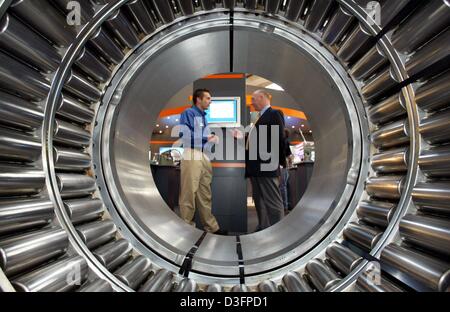 (Dpa) - zwei Menschen sind zu sehen durch ein Rollenlager auf dem Stand der US-amerikanischen Firma Timken aus Ohio, bei der industriellen Handel Messe Hannover Messe (Hannover Messe) in Hannover, Deutschland, 7. April 2003. Ca. 6.200 Aussteller zeigen ihre Produkte auf der weltweit größten Messe für Industrie vom 7. April bis 12. April 2003. Stockfoto