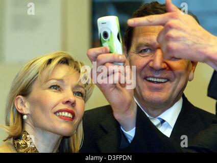 (Dpa) - Bundeskanzler Gerhard Schroeder und seine Frau Doris Schröder-Koepf Blick auf ein neues Mobiltelefon mit integrierter Kamera auf dem Marktstand von Nokia, bei der weltweit größten Computer Messe CeBIT in Hannover, 12. März 2003 zu handeln. Die CeBIT wird voraussichtlich vom 12. bis 19. März 2003 stattfinden. Sollen mehr als 6.500 Unternehmen aus der ganzen Welt präsentieren ihre produ Stockfoto