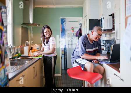 Ein paar verbringen das Wochenende in der Küche, wo die Frau kocht, während Ehemann das Rezept im Internet sieht Stockfoto